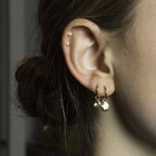 our charmed hoops with mixed charms: disc, star, and diamond slice; top earrings are 9ct gold etched studs with crystals and gold plated tiny flower studs, both available at feltlondon.com  